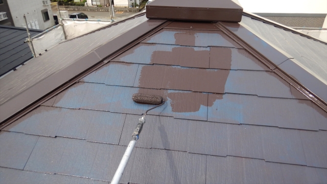 屋根の頭頂部を塗装する様子